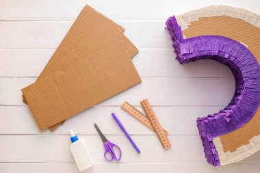 Beyaz ahşap arka planda gökkuşağı şeklinde Meksika pinyatası yapmak için malzemeler