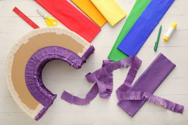 Beyaz ahşap arka planda gökkuşağı şeklinde Meksika pinyatası yapmak için malzemeler