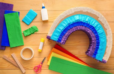 Tahta arka planda gökkuşağı şeklinde Meksika pinyatası yapmak için malzemeler