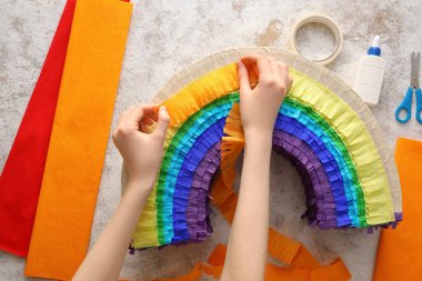 Kadın, arka planda gökkuşağı şeklinde Meksika pinyatası yapıyor.