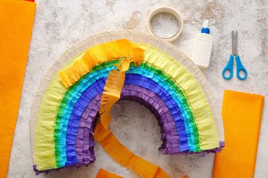 Arkaplanda gökkuşağı şeklinde Meksika pinyatası yapmak için malzemeler