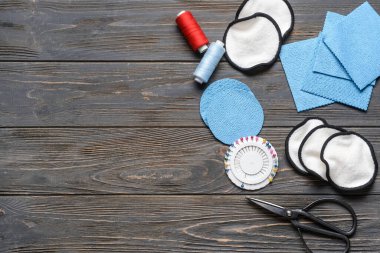 Koyu ahşap arka planda malzeme içeren el yapımı pamuk pedler.