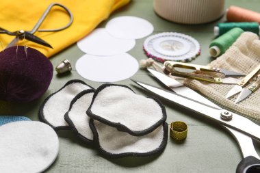 Yeşil ahşap arka planda malzeme içeren el yapımı pamuk pedler, yakın plan.