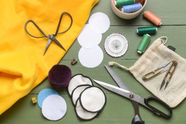 Yeşil ahşap arka planda malzeme içeren el yapımı pamuk pedler.