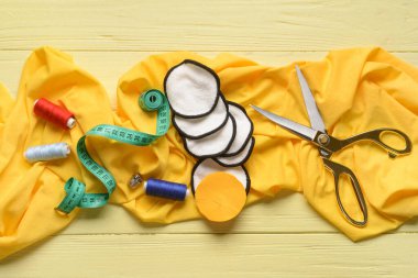 Sarı ahşap arka planda malzeme içeren el yapımı pamuk pedler.