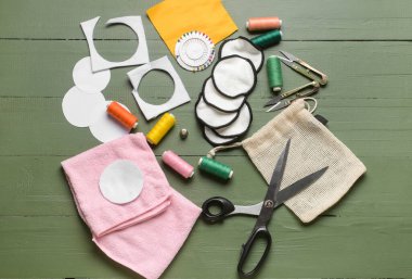 Yeşil ahşap arka planda malzeme içeren el yapımı pamuk pedler.