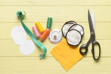 Sarı ahşap arka planda malzeme içeren el yapımı pamuk pedler.