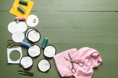 Yeşil ahşap arka planda malzeme içeren el yapımı pamuk pedler.