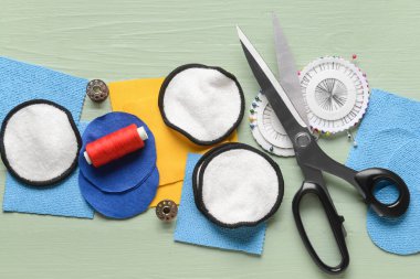 Yeşil ahşap arka planda malzeme içeren el yapımı pamuk pedler.