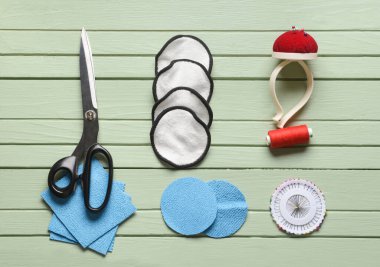 Yeşil ahşap arka planda materyalleri olan el yapımı yeniden kullanılabilir pamuk yastıklar.