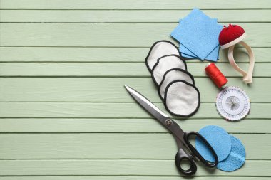 Yeşil ahşap arka planda materyalleri olan el yapımı yeniden kullanılabilir pamuk yastıklar.