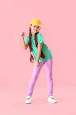 Pembe arka planda dans eden şapkalı şirin küçük kız.