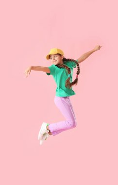 Pembe arka planda zıplayan şapkalı şirin küçük kız.