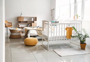 Beşiği ve büyük penceresi olan aydınlık, modern yatak odası.