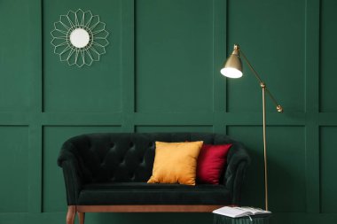 Yeşil duvarın yanında şık koltuğu olan modern bir iç mekan.