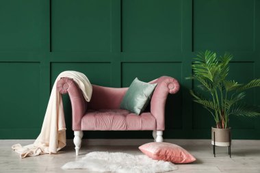 Yeşil duvarın yanında şık koltuğu olan modern bir iç mekan.