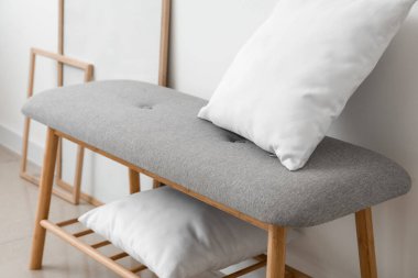 Işık duvarının yanında yastıkları olan rahat bir bank