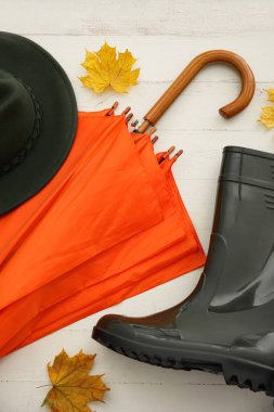 Parlak şemsiye, şapka ve lastik çizmeler açık ahşap arka planda, yakın plan