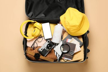 Renk arkaplanında paketlenmiş seyahat eşyalarıyla dolu bavul