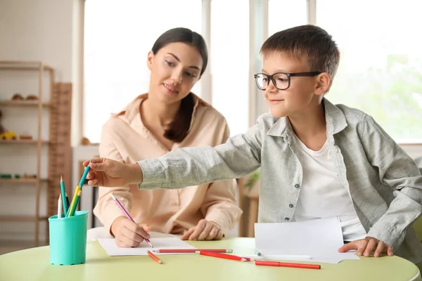 Küçük çocuk evde ablasıyla resim çiziyor.