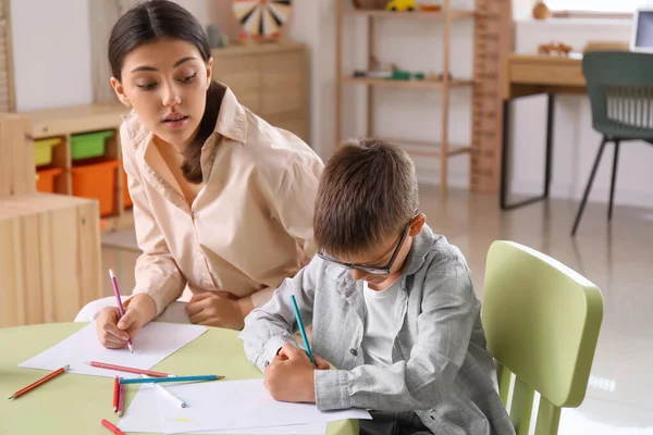 Küçük çocuk evde ablasıyla resim çiziyor.