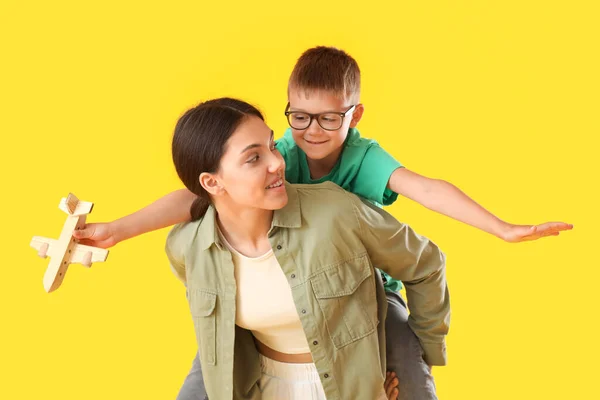 Adolescente Carregando Pickaback Seu Irmãozinho Com Avião Madeira Fundo Amarelo — Fotografia de Stock