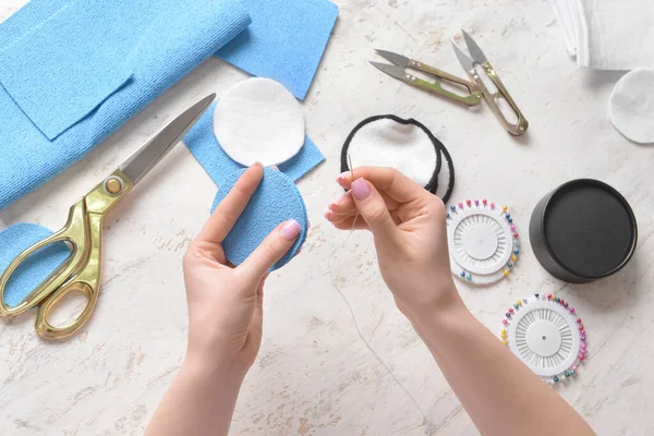 Yeniden kullanılabilir pamuk yastık için iğne ve kumaş kullanan kadın.