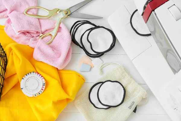 Beyaz ahşap arka planda malzeme içeren el yapımı pamuk pedler.