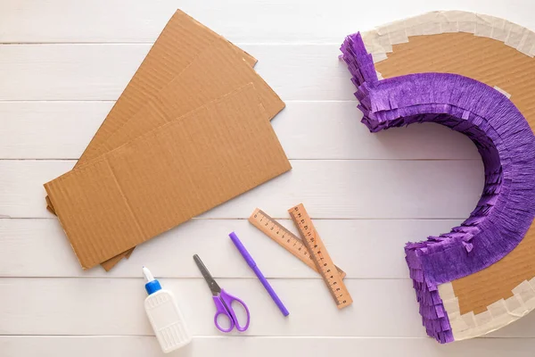 Beyaz ahşap arka planda gökkuşağı şeklinde Meksika pinyatası yapmak için malzemeler