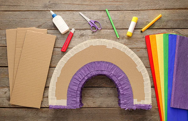 Tahta arka planda gökkuşağı şeklinde Meksika pinyatası yapmak için malzemeler