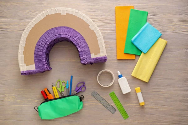 Tahta arka planda gökkuşağı şeklinde Meksika pinyatası yapmak için malzemeler