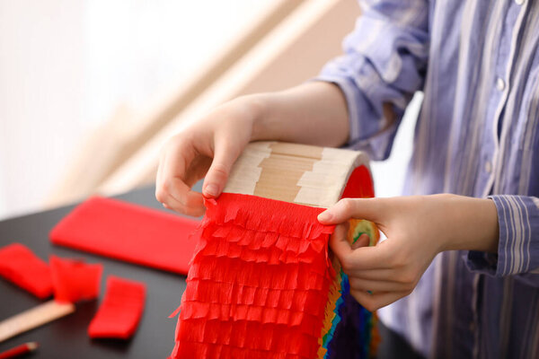 Woman making Mexican pinata in shape of rainbow on table at home, closeup