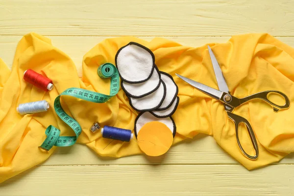 Sarı ahşap arka planda malzeme içeren el yapımı pamuk pedler.