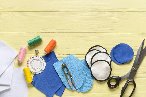 Sarı ahşap arka planda malzeme içeren el yapımı pamuk pedler.