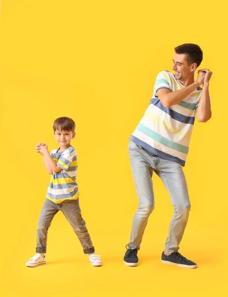 Dancing man and his little son on color background