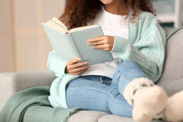Young African American Woman Blue Cardigan Reading Book Sofa Home — Stock Photo, Image