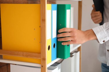 Ofiste belgelerle çalışan genç adam.