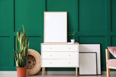 Boş çerçeveli çekmeceler ve yeşil duvarın yanında saksı