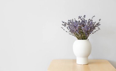 Masanın üzerinde açık arkaplanda güzel lavanta çiçekleri olan vazo