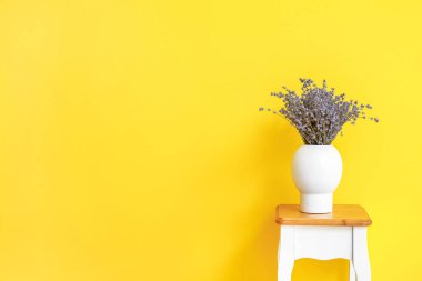 Masanın üzerinde güzel lavanta çiçekleri olan vazo renk arkaplanına karşı