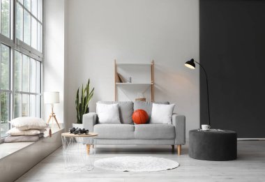 Kanepe, puf ve raf üniteli aydınlatma odasının içinde.