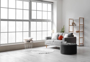 Kanepe, puf ve raf üniteli aydınlatma odasının içinde.