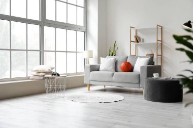 Kanepe, puf ve raf üniteli aydınlatma odasının içinde.