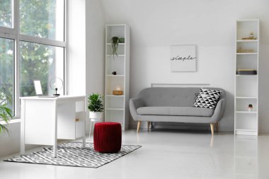 Kanepesi ve kırmızı pouf 'u olan bir oturma odası.