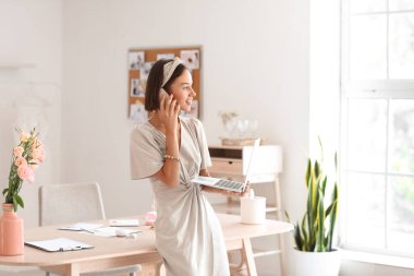 Kadın düğün organizatörü ofiste telefonla konuşuyor.