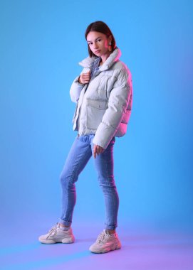 Renkli arka planda şık ve sıcak kıyafetler içinde güzel bir genç kadın.