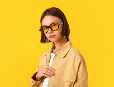 Renkli arka planda şık giyinmiş güzel bir genç kadın.