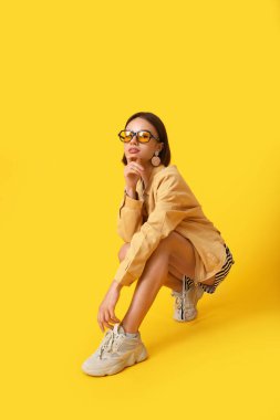 Renkli arka planda şık giyinmiş güzel bir genç kadın.