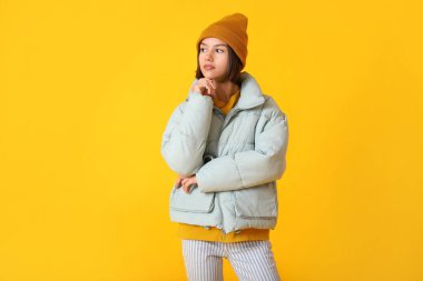 Renkli arka planda şık ve sıcak kıyafetler içinde güzel bir genç kadın.