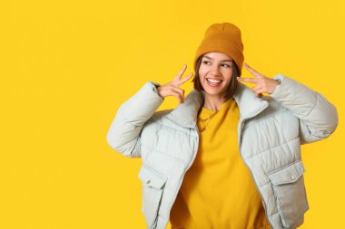 Renkli arka planda şık ve sıcak kıyafetler giyen havalı genç bir kadın.